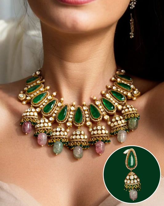 Emerald Jhumka Moissanite Necklace Set featuring a statement gold-plated necklace with deep green emerald-cut stones, sparkling moissanite detailing, pearl accents, and multicolour gemstone jhumka drops, paired with matching jhumka earrings.