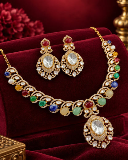 Luxury multicolor gemstone necklace and matching earrings displayed on rich burgundy velvet, featuring intricate gold detailing, clear crystal accents, and vibrant red, green, blue, yellow, and white gemstones