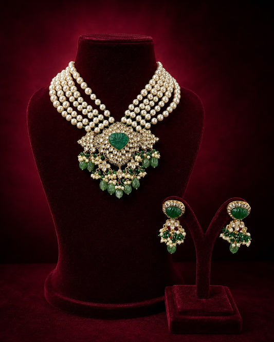 Alt text: Elegant green gemstone and pearl drop earrings with gold detailing, arranged as a pair on rich burgundy velvet in a luxury flat-lay jewellery setting.