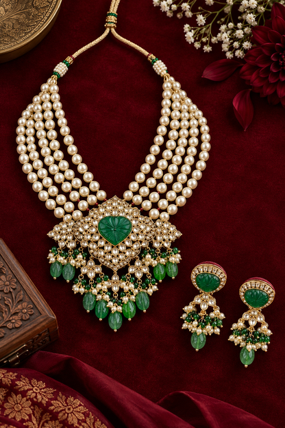 Alt text: Elegant green gemstone and pearl drop earrings with gold detailing, arranged as a pair on rich burgundy velvet in a luxury flat-lay jewellery setting.